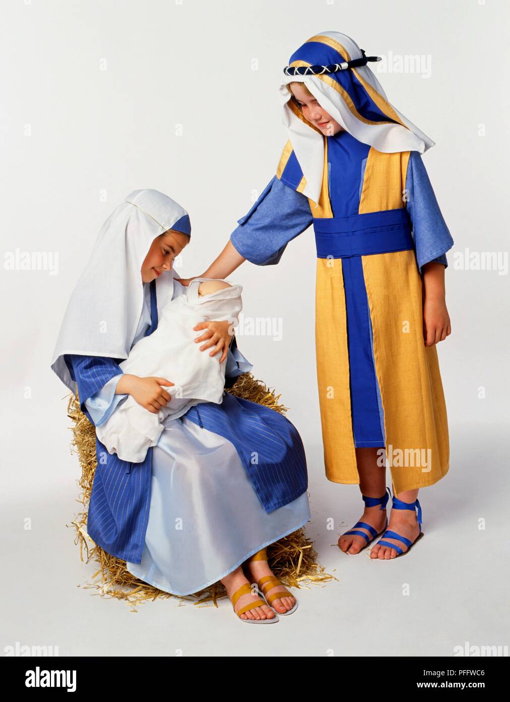 Garçon vêtu comme Joseph debout sur boy Mary de câliner un enveloppé l'Enfant Jésus Banque D'Images