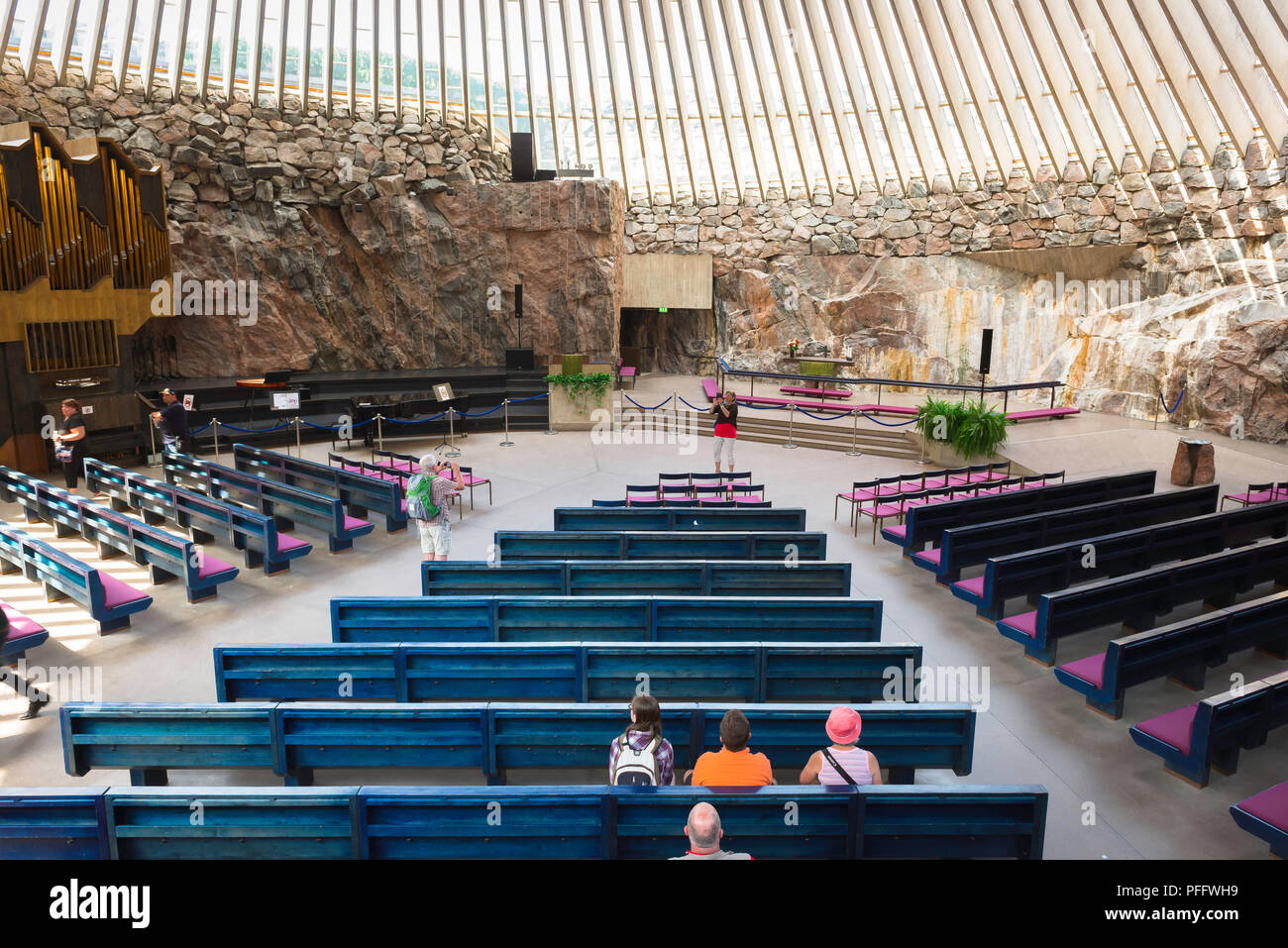 L'église Temppeliaukio, Temppeliaukion Kirkko vue à l'intérieur de l'église de Roche 'ou', dans le centre d'Helsinki montrant les touristes assis sur son banc bleu, en Finlande. Banque D'Images