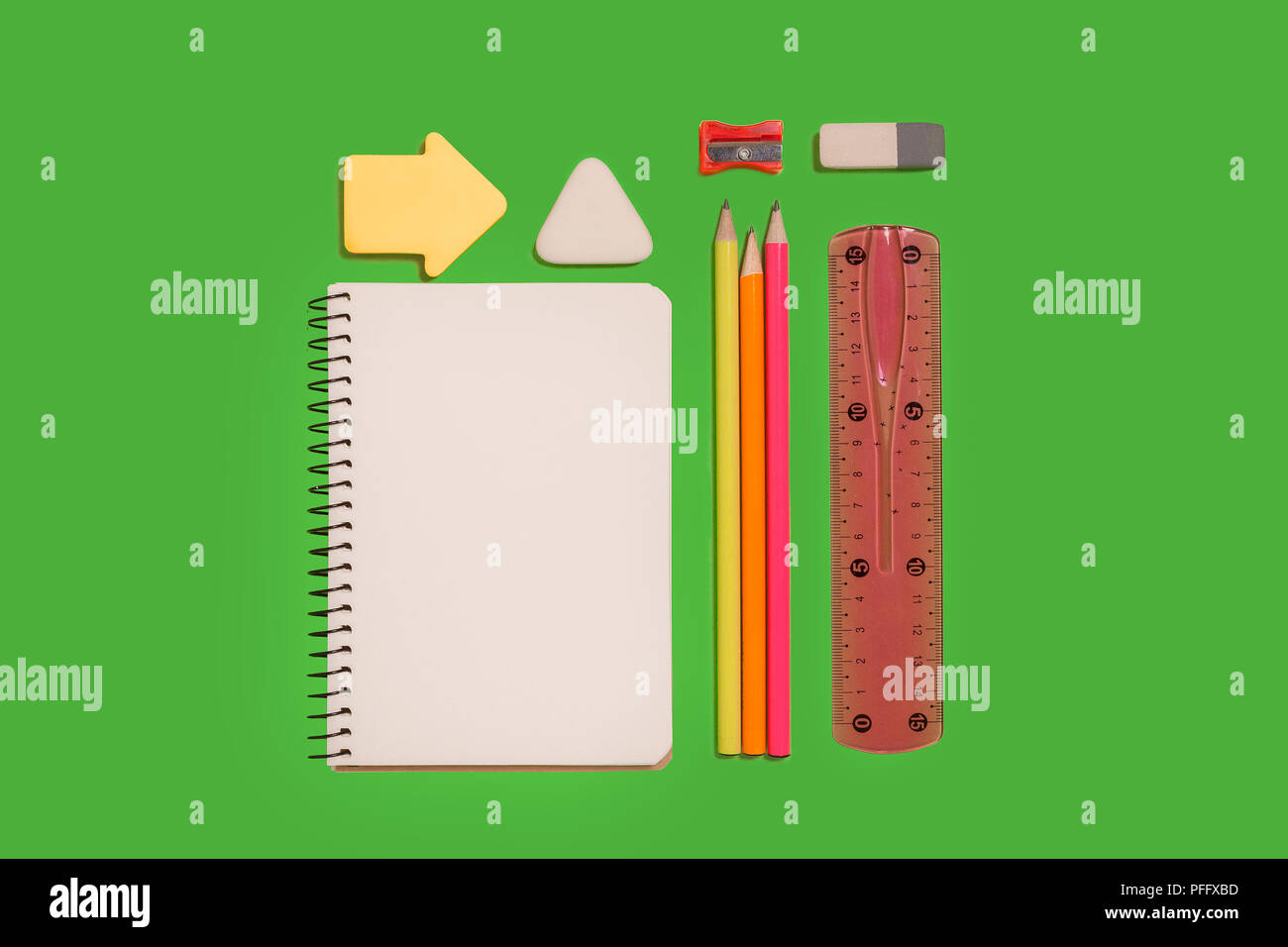 Bloc-notes, crayons, autocollants, une gomme et un accrochage posé sur une surface verte. concept de l'éducation ou de secrétariat chancellerie. espace libre pour la publicité Banque D'Images