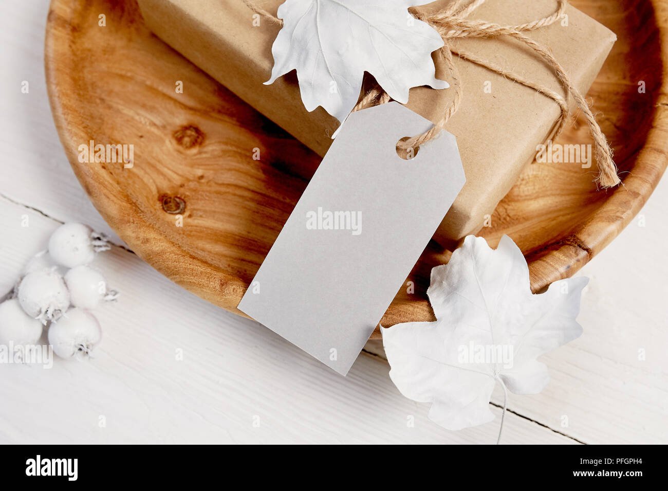 Lieu d'accueil en bois avec des cadeaux et l'étiquette. Les baies et les feuilles blanches sur une maquette en bois automne fond. Carte de souhaits pour le jour d'action de grâce dans un style rustique avec de l'espace pour votre texte. Mise à plat. Vue d'en haut Banque D'Images