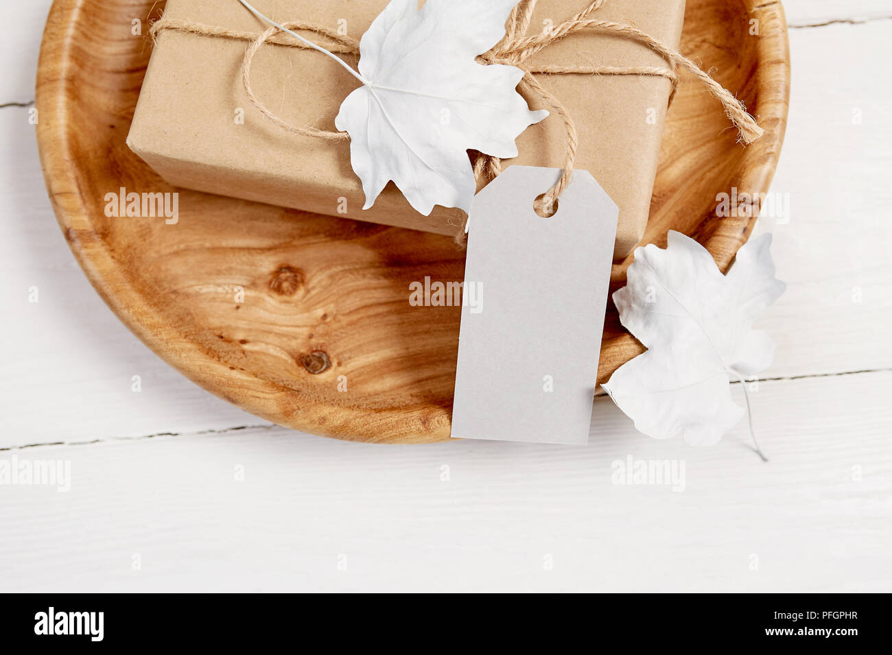 Lieu d'accueil en bois avec des cadeaux et l'étiquette. Les baies et les feuilles blanches sur une maquette en bois automne fond. Carte de souhaits pour le jour d'action de grâce dans un style rustique avec de l'espace pour votre texte. Mise à plat. Vue d'en haut Banque D'Images