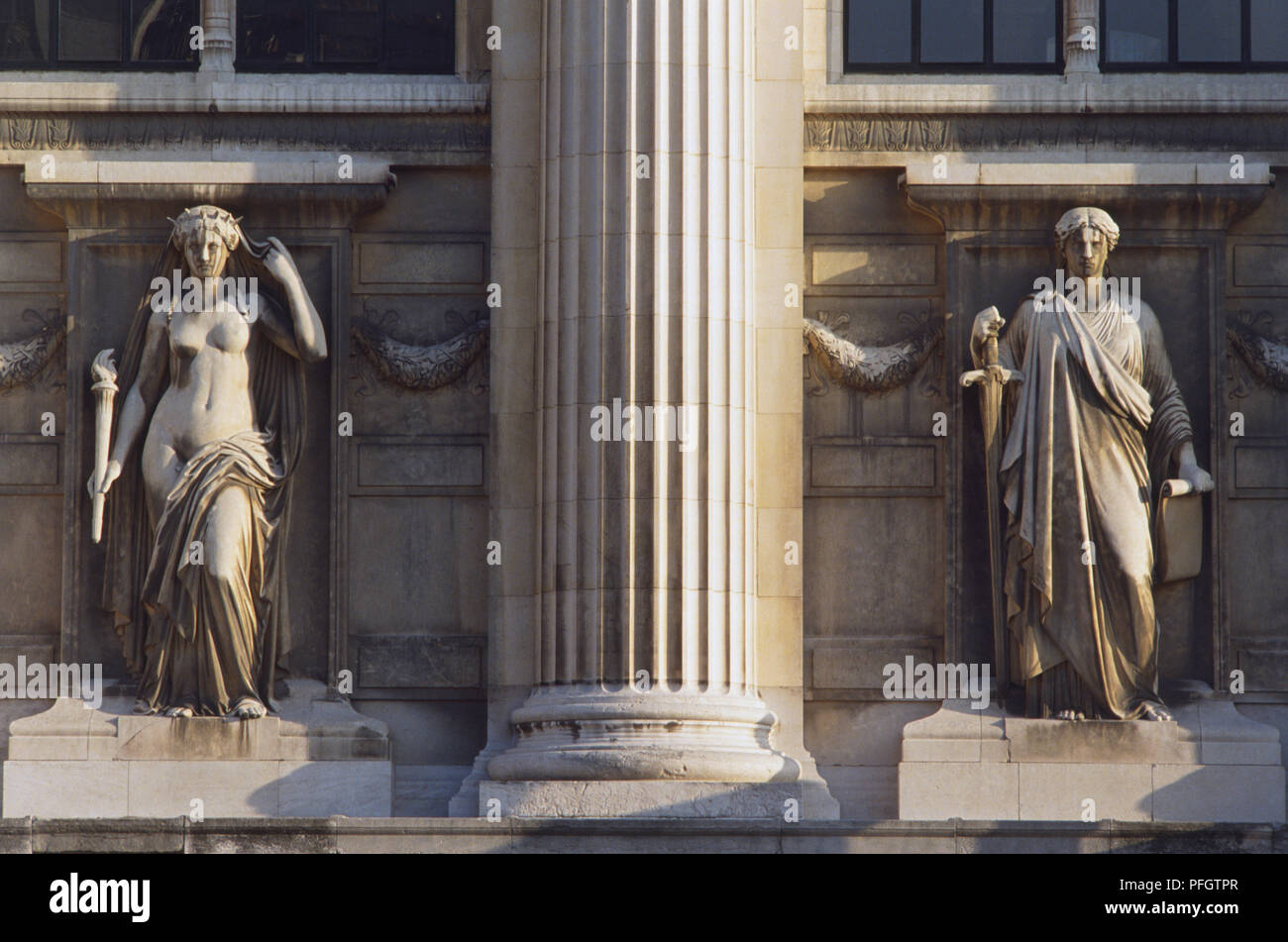 France, Paris, Palais de Justice, avec des statues en pierre de l'homme et de la femme, deux statues en pierre de personnes de chaque côté de la colonne. Banque D'Images