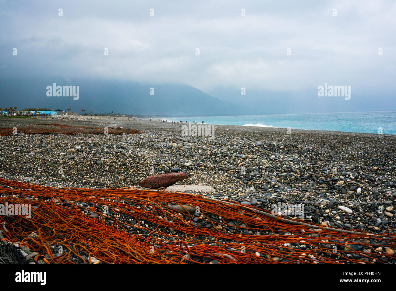 Filet de pêche rouge sur la plage de galets avec de l'océan Pacifique et montagnes en arrière-plan dans la zone panoramique de Qixingtan Taiwan Hualien Banque D'Images