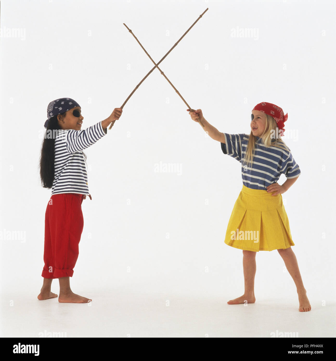 Deux jeunes filles en costumes pirate crossing twig 'swords', side view Banque D'Images