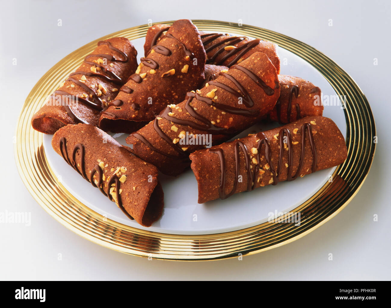 Tuiles au chocolat, chocolat-hazlenut arrosé curly s'enclenche sur plateau d'or, Close up. Banque D'Images