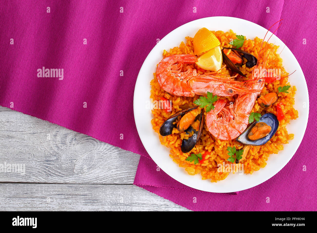 Partie de la paella de Valence de fruits de mer gastronomique avec des langoustines, des moules sur le riz et crémeuse salé avec des épices et des tranches de citron sur plaque, sur tapis de table Banque D'Images