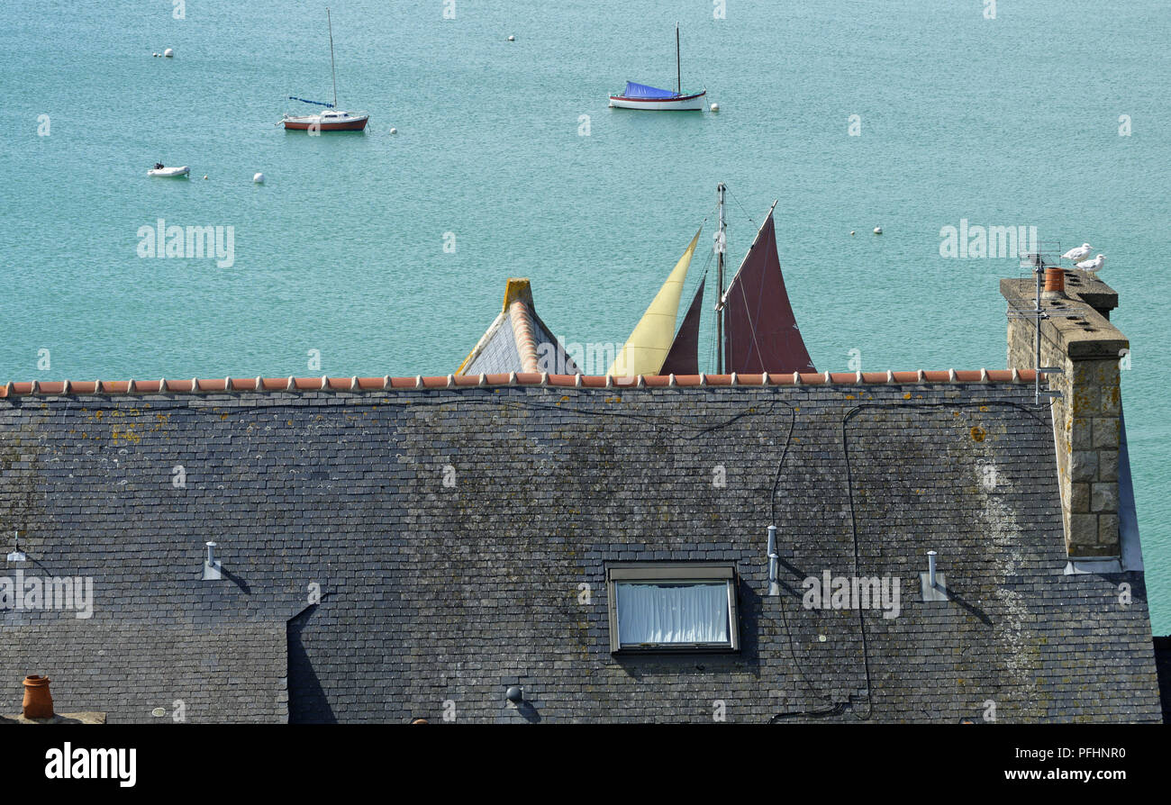 Voiles d'un bateau traditionnel à l'arrière-plan d'un toit, port de la Houle à Cancale (Bretagne, France). Banque D'Images