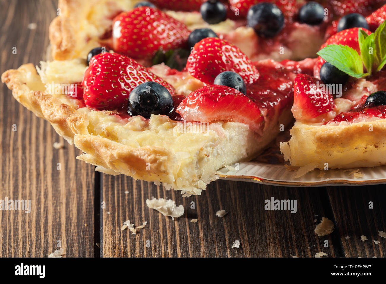 Tarte de fromage blanc, les fraises et les bleuets, décoré de feuilles de menthe Banque D'Images