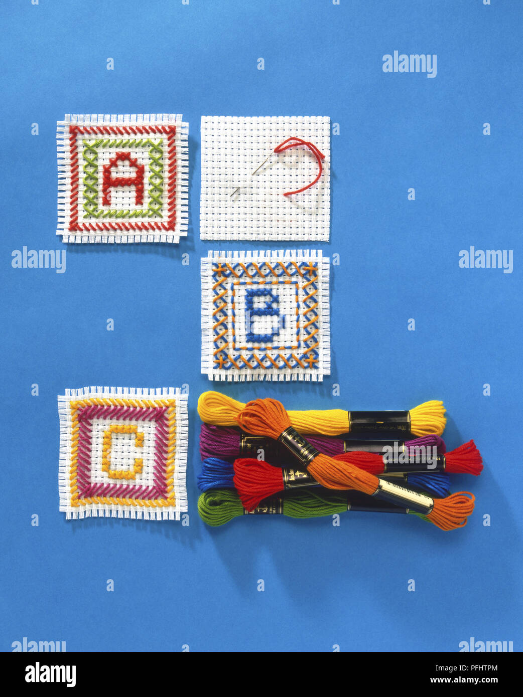 Les lettres A, B et C contre-cousus en carrés distincts de tissu blanc, boules colorées empilées de fil de soie, vue de dessus Banque D'Images