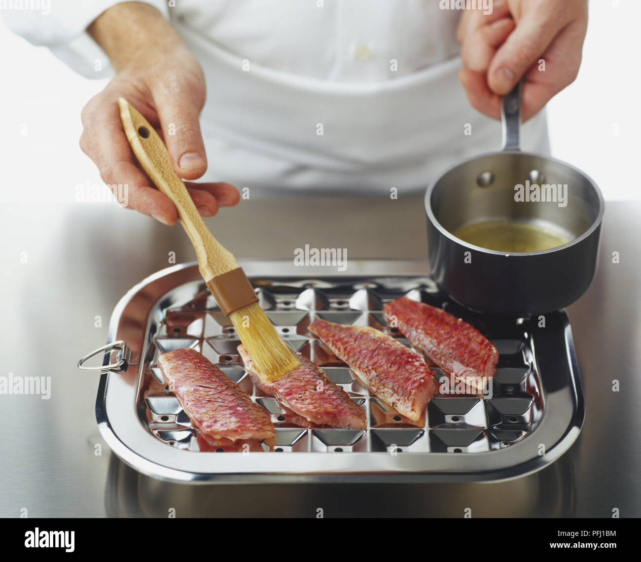 Filets de rougets 4 sur le châssis d'une poêle avec du beurre fondu brossé étant Banque D'Images