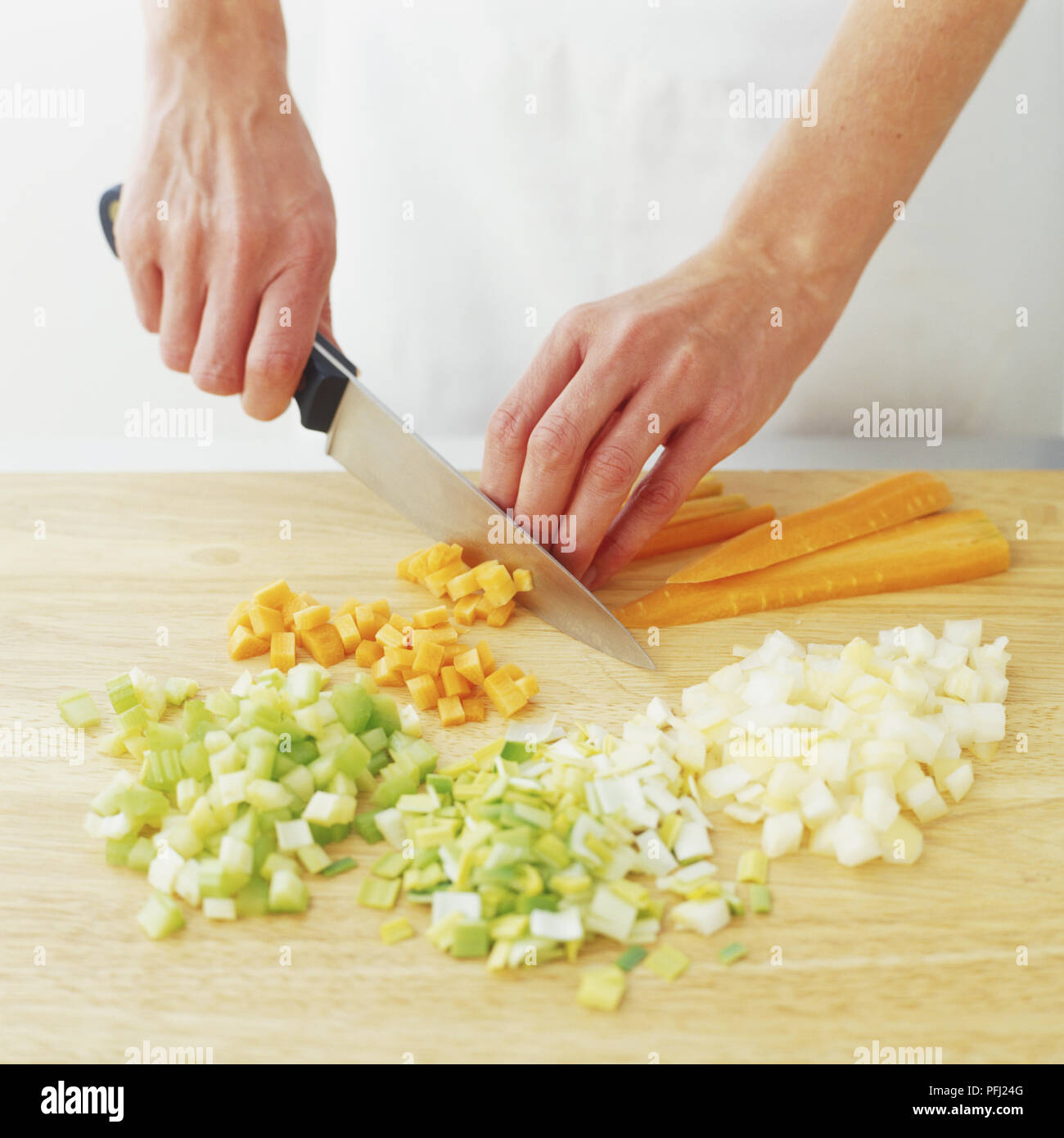 L'oignon, le poireau, le céleri et les carottes en dés en bois sur planche, vue avant Banque D'Images