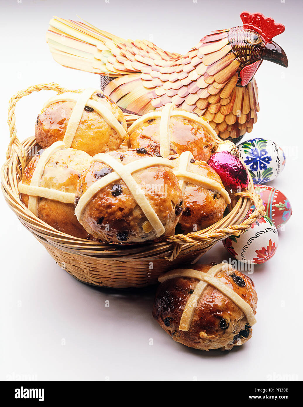 Les brioches dans un panier, à côté de poulet et oeufs peints en bois Banque D'Images