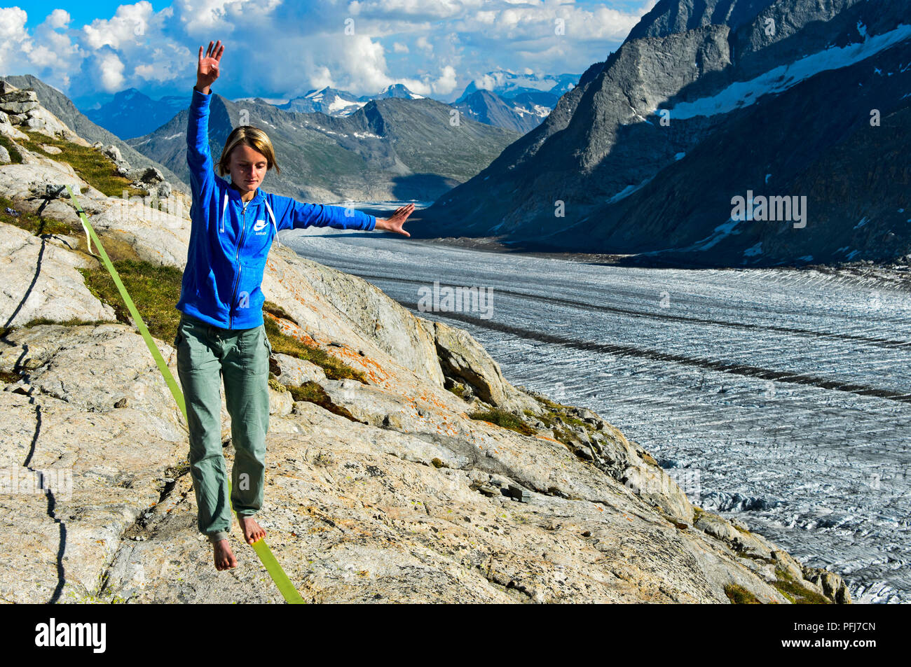 Jeune femme est en équilibre sur le slackline au refuge Konkordia sur le glacier d'Aletsch, Alpes Bernoises, Valais, Suisse Banque D'Images