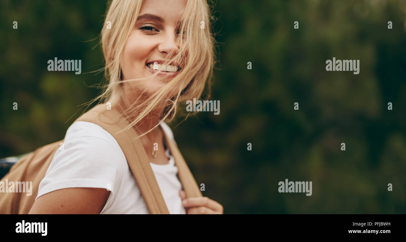 Close up of woman sur une maison de vacances dans un parc à pied portant un sac. Portrait d'une femme avec les cheveux bruns volant au-dessus de son visage. Banque D'Images