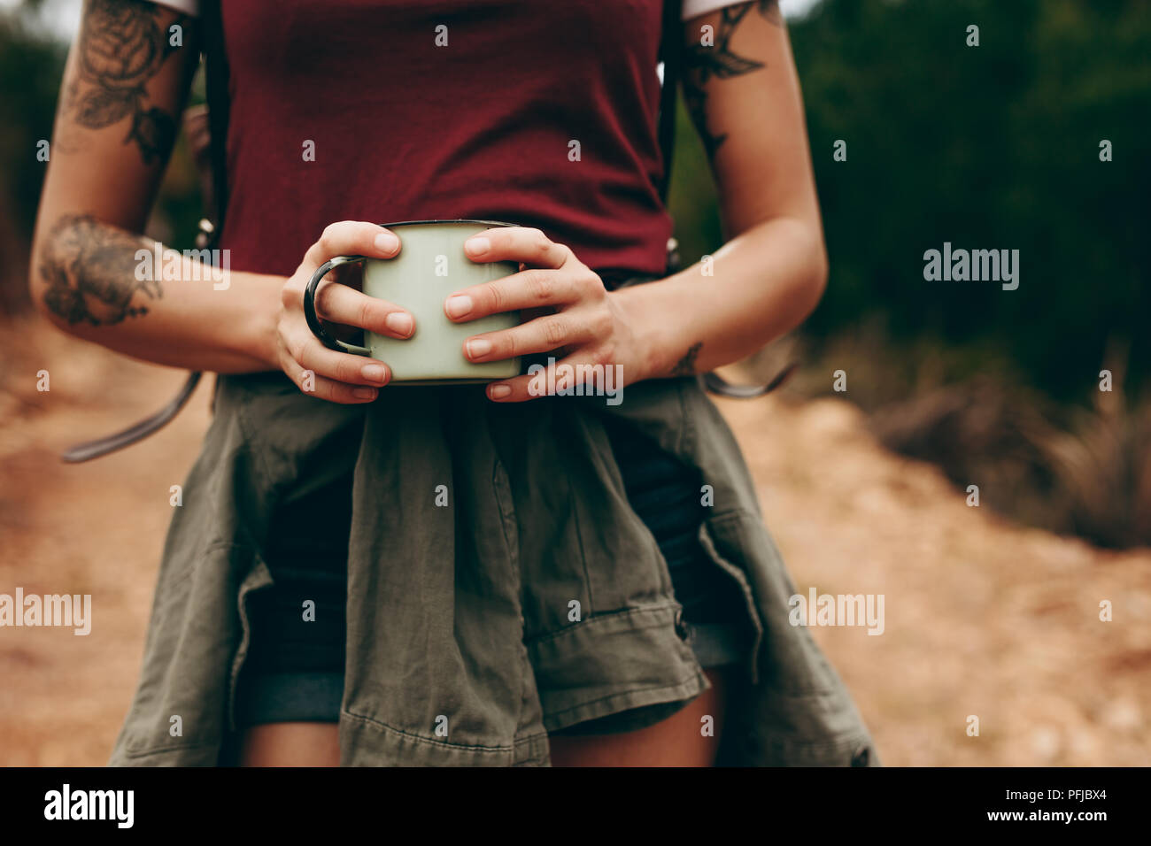 Close up of mid section d'un voyageur woman holding tasse à café avec les deux mains. Maison de vacances sur une femme marche à travers une forêt. Banque D'Images