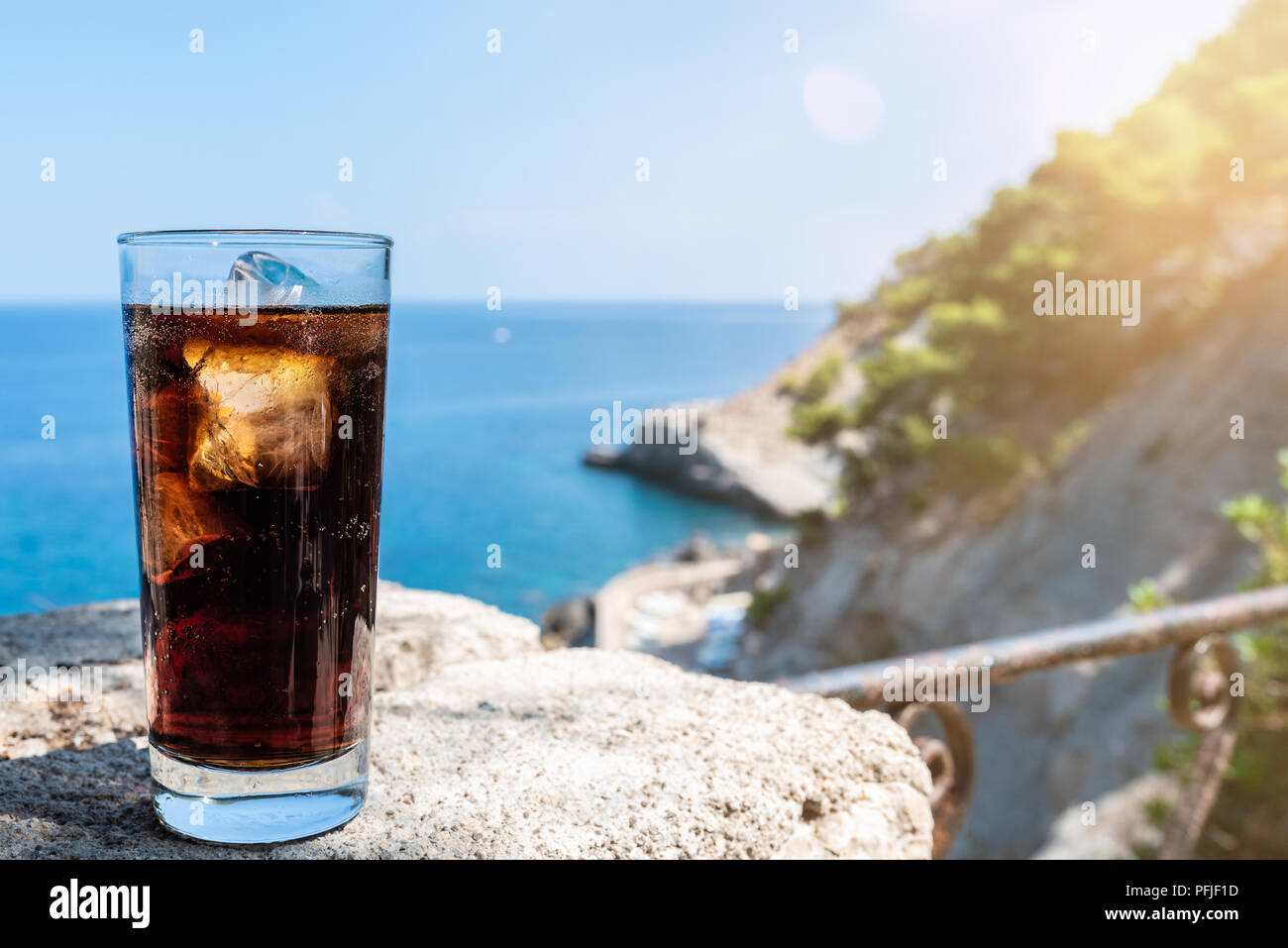 Cola glacé dans de grands verres de boisson contre la mer et le ciel bleu Banque D'Images