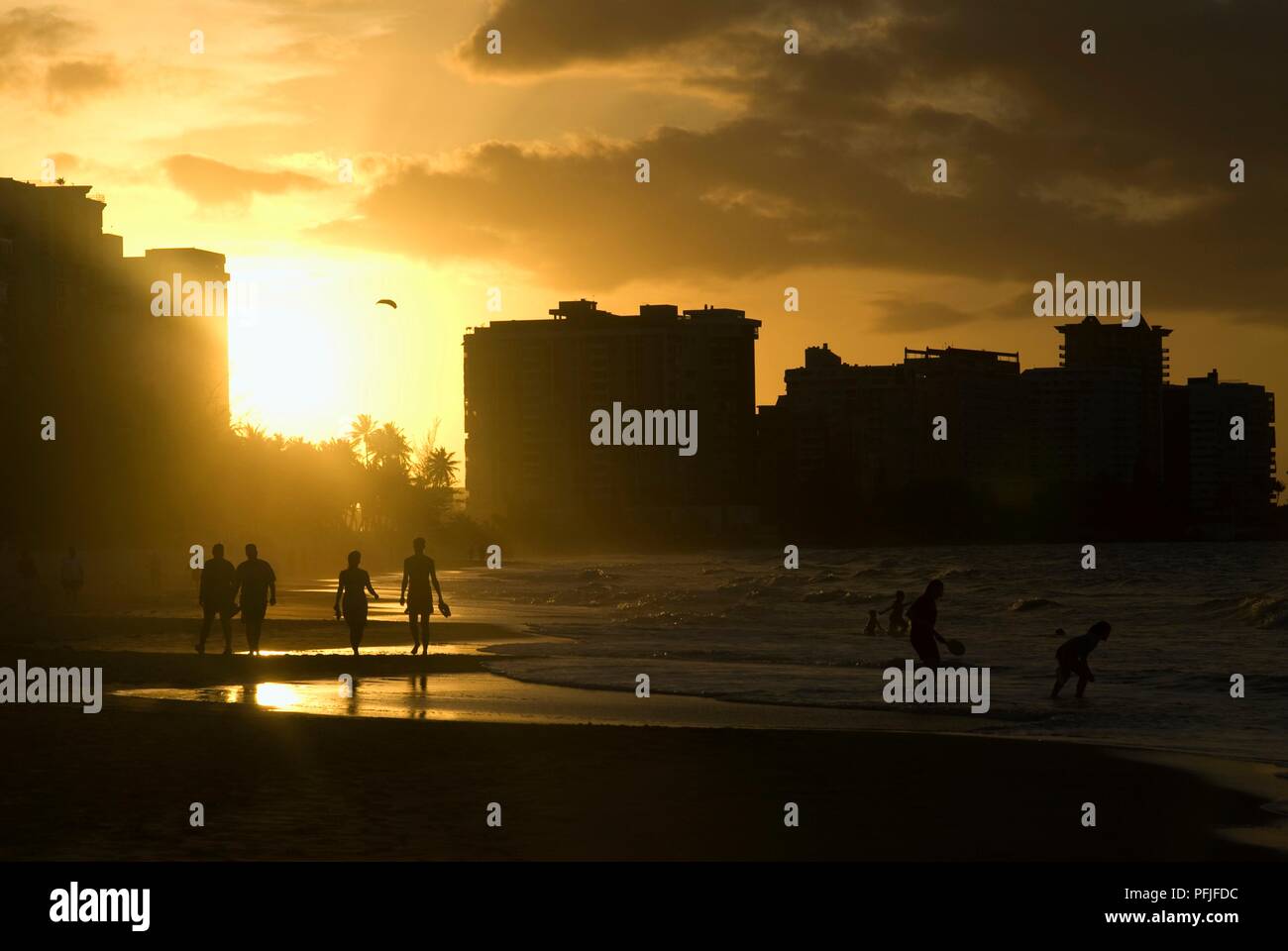 Puerto Rico, Carolina, silhouettes de promeneurs sur la plage à Isla Verde, coucher du soleil Banque D'Images