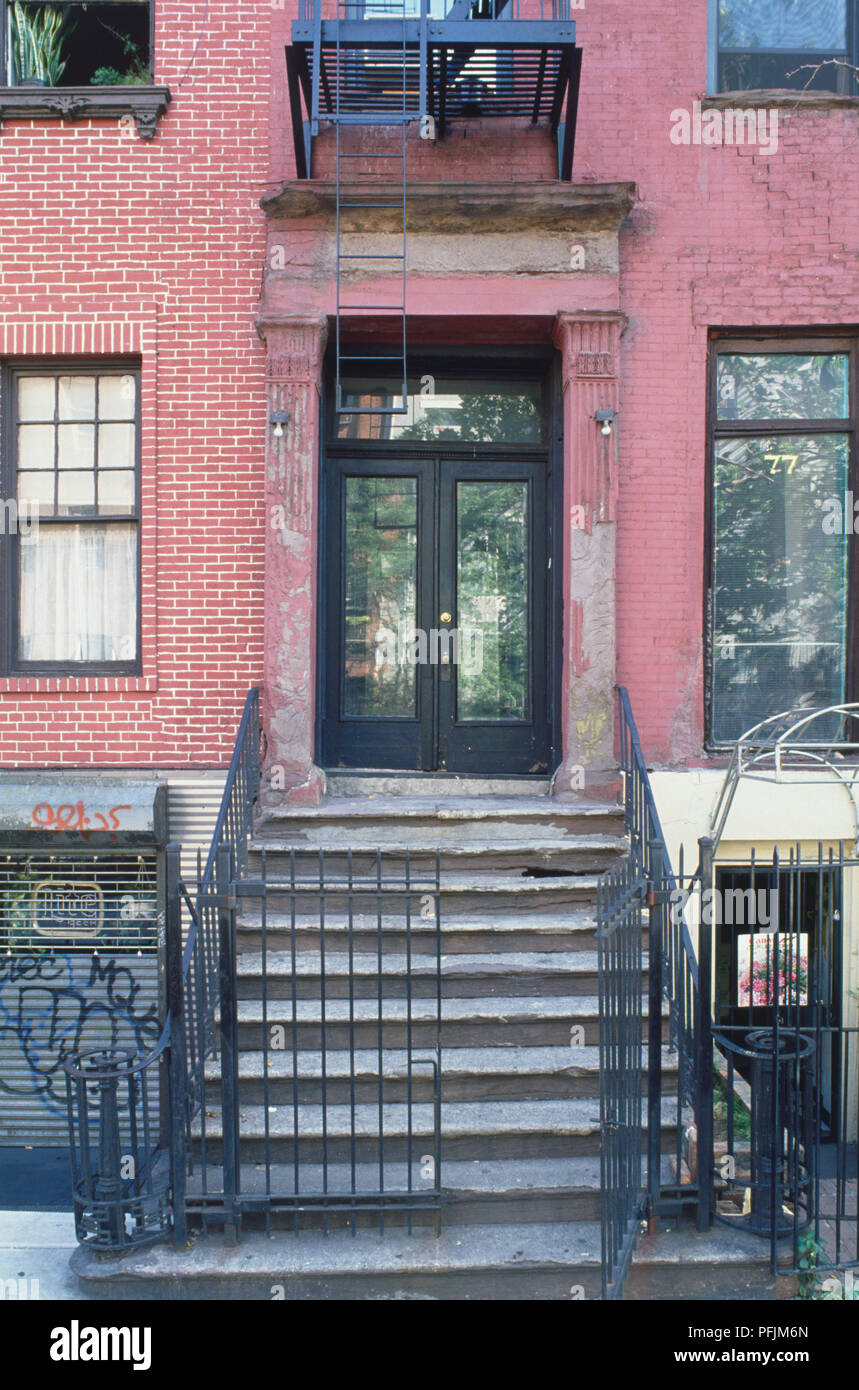 USA, New York, détail de façade en briques rouges, montrant la porte avant ouverte et les étapes menant à une porte en verre. Banque D'Images