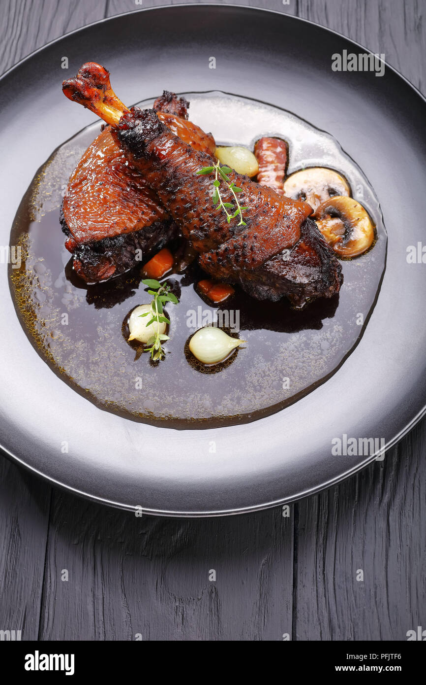 Portion de ragoût de poulet savoureux - braisé de cuisse et le pilon avec le vin, les herbes, les champignons et les légumes servis sur la plaque noire, recette authentique français Banque D'Images