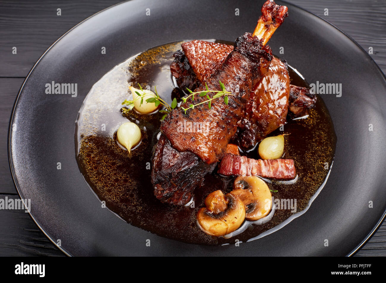 Une partie de ragoût de poulet savoureux - braisé de cuisse et le pilon avec le vin, les herbes, les champignons et les légumes servis sur la plaque noire sur la table en bois, festiv Banque D'Images
