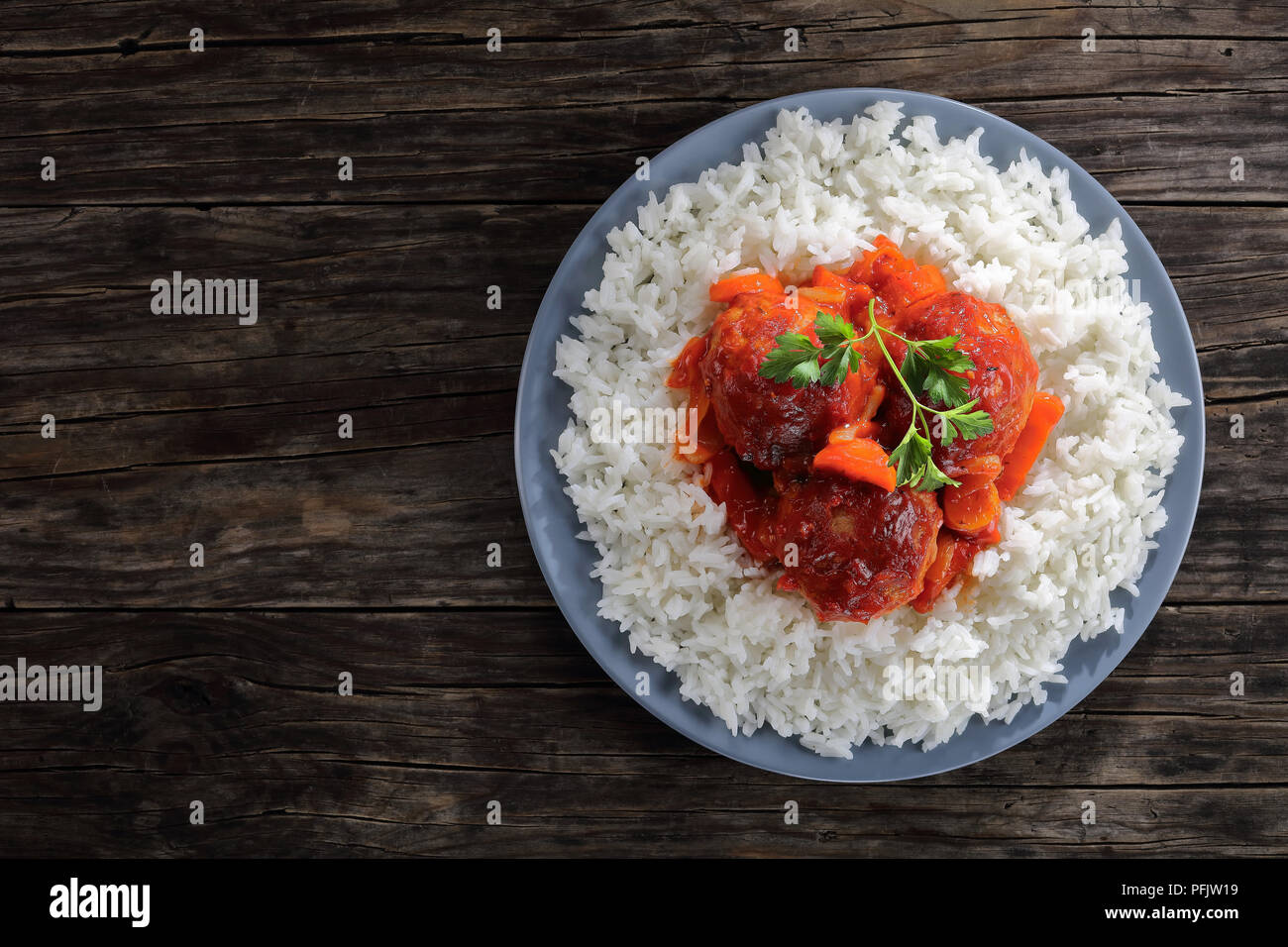 Chaud savoureux braisé Boulettes de dinde à la sauce tomate et légumes servi avec du riz long grain sur une plaque gris sur table en bois sombre, vue d'en haut Banque D'Images