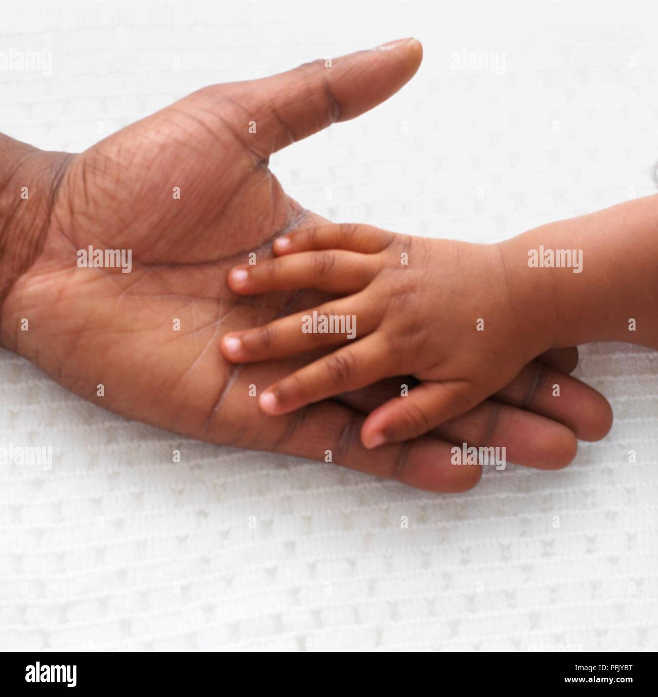 Baby Boy's hand on man's palm, close-up Banque D'Images
