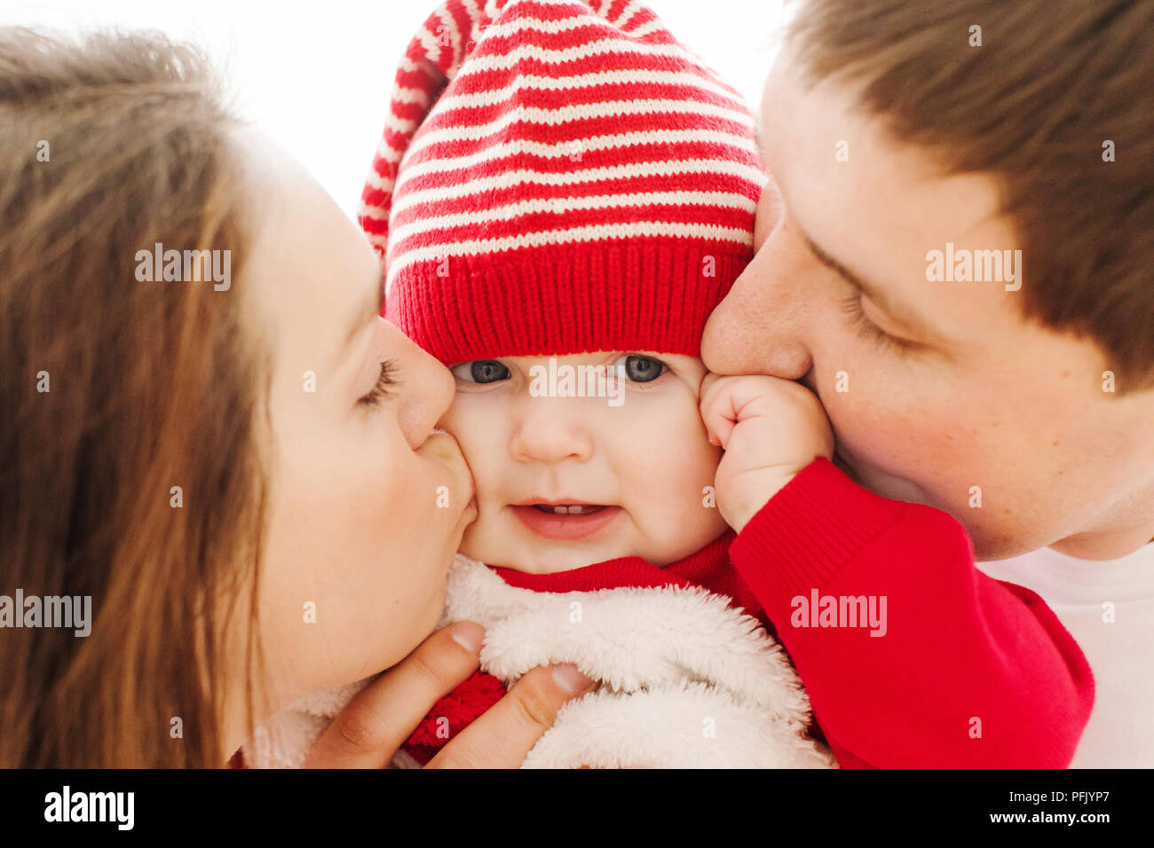 Les parents embrassant bébé aux joues Banque D'Images