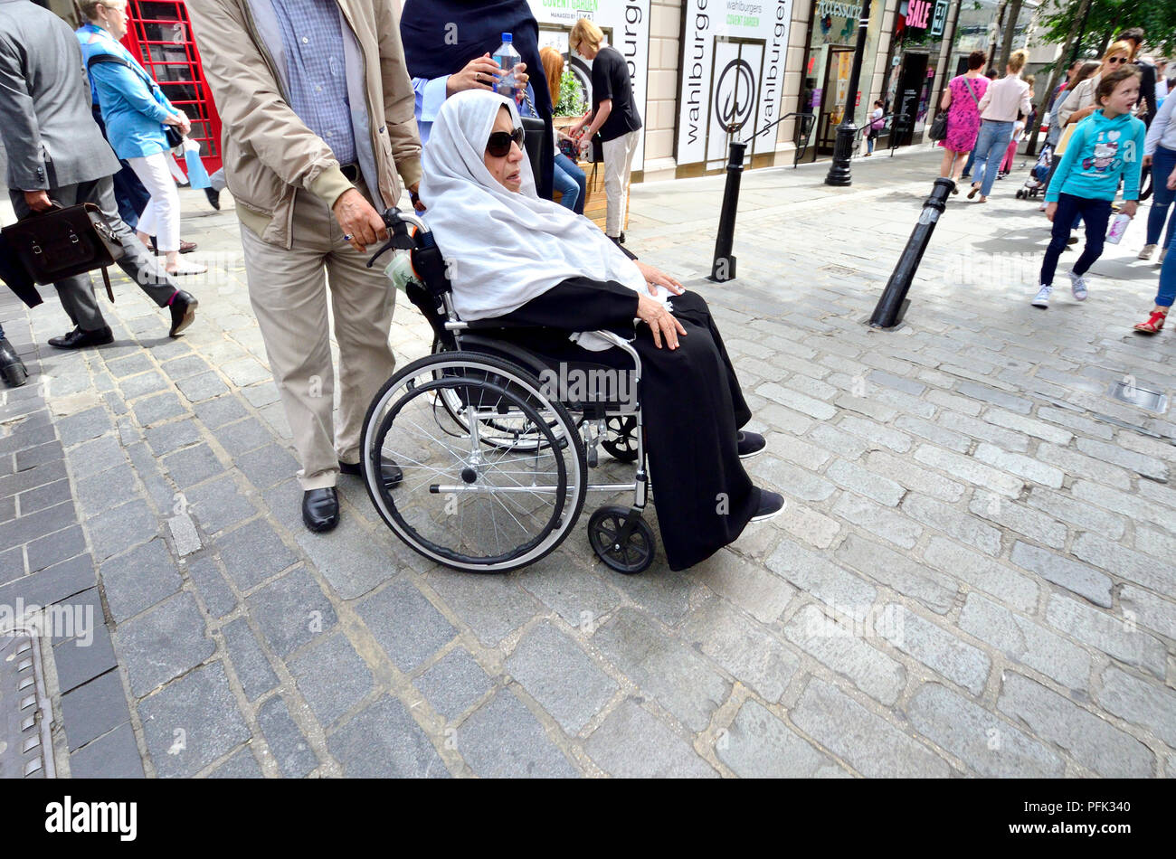 Femme musulmane avec foulard dans un fauteuil roulant, Covent Garden, Londres, Angleterre, Royaume-Uni. Banque D'Images