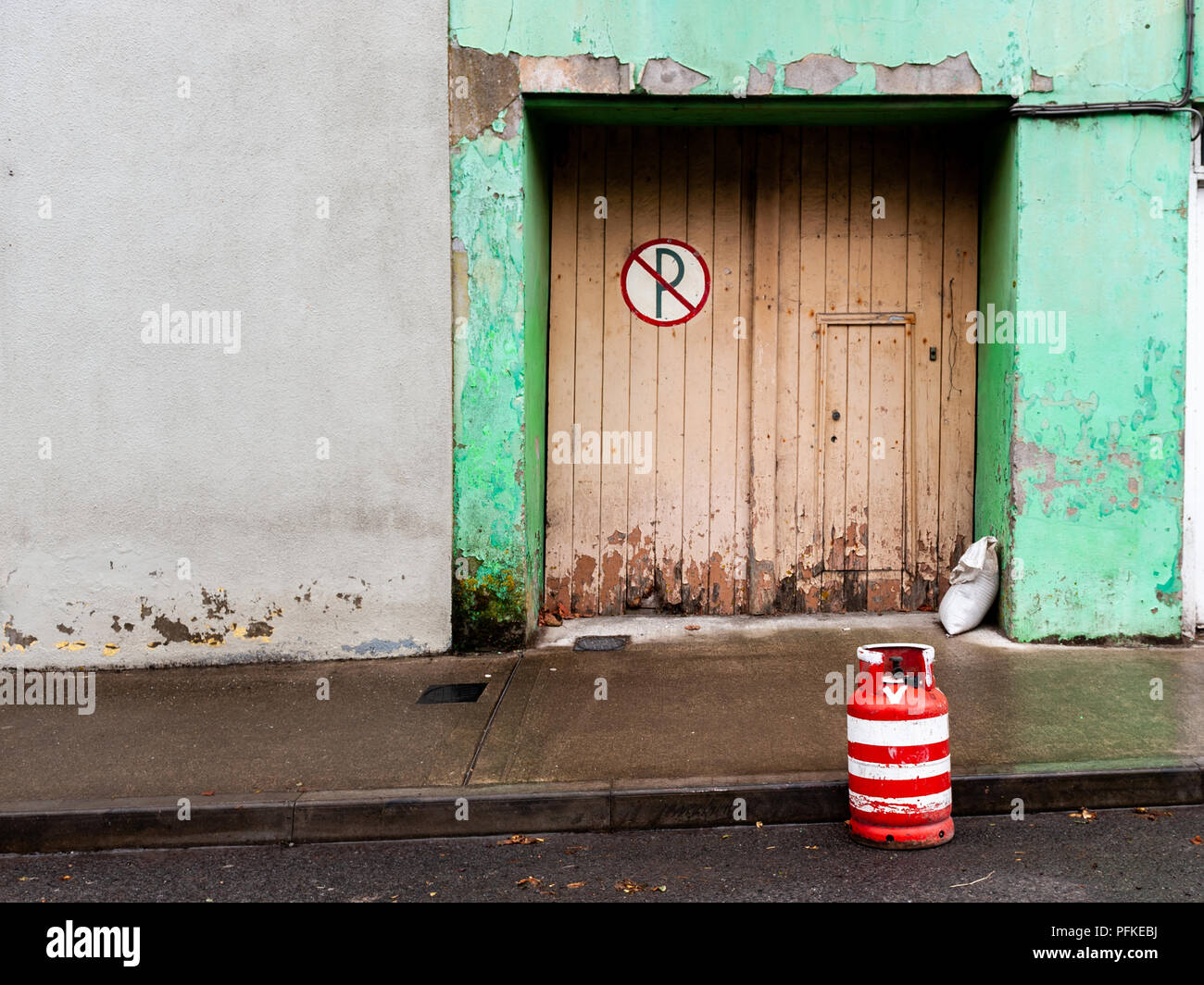 Bouteille de gaz vide peint en rouge et blanc à agir comme une route/traffic cone dans North Street, Baltimore, West Cork, Irlande avec copie espace. Banque D'Images