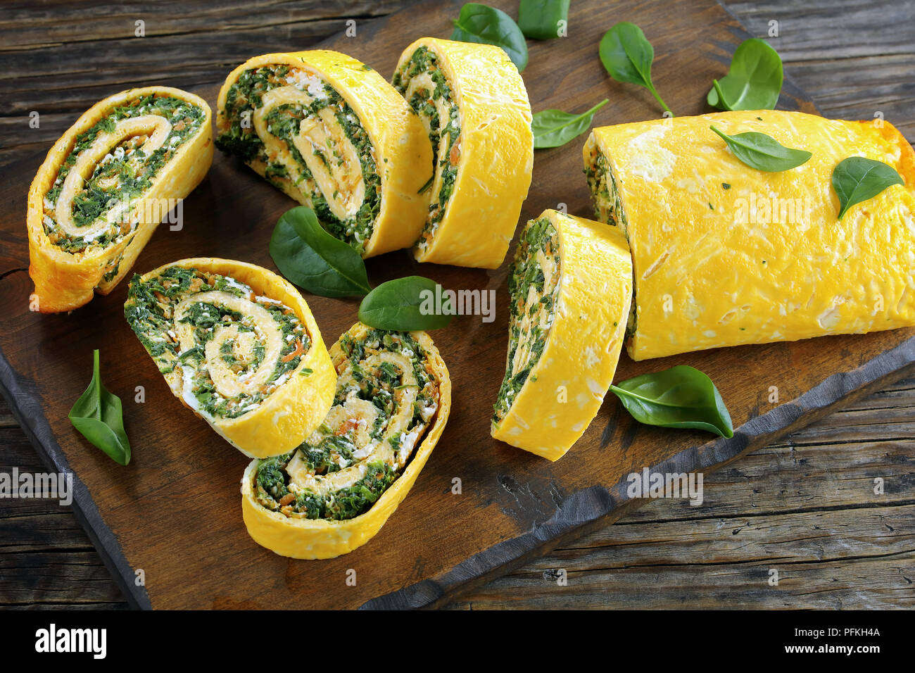 Roulade oeufs délicieux avec un remplissage de mélange d'épinards, la feta et les carottes coupées en rondelles sur les planches à découper en bois, table en bois foncé sur la vue, Banque D'Images