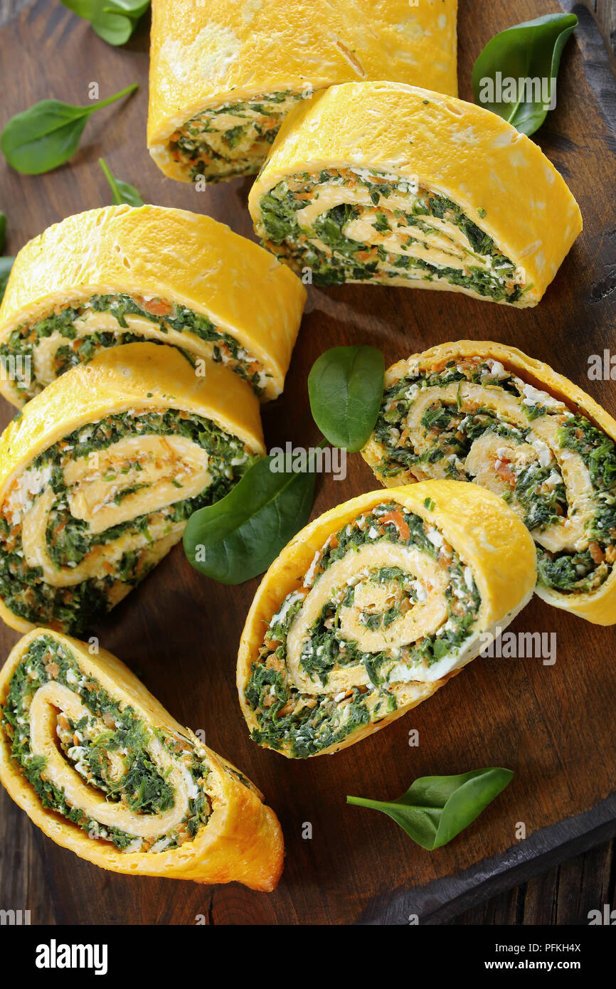 Roulade oeufs délicieux avec un remplissage de mélange d'épinards, la feta et les carottes sur les planches à découper en bois, table en bois foncé, sur la vue verticale d'en haut Banque D'Images