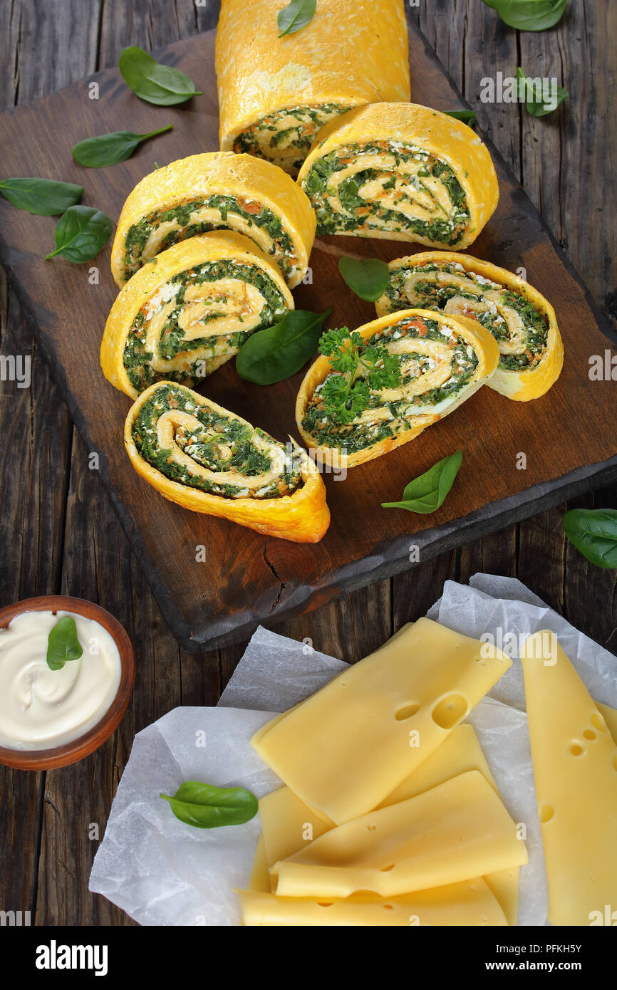 Roulade oeufs délicieux avec un remplissage de mélange d'épinards, la feta et les carottes coupées en tranches sur les planches à découper en bois avec la sauce et du fromage à foregro Banque D'Images