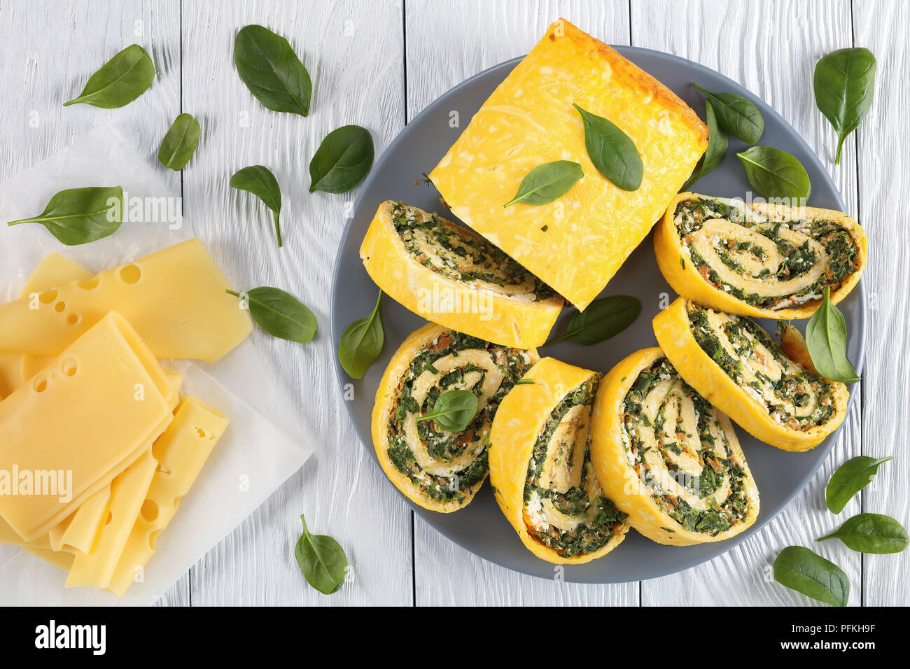 Roulade oeufs délicieux avec un remplissage de mélange d'épinards, la feta et les carottes coupées en tranches sur la plaque grise sur table en bois avec des ingrédients à backgrou Banque D'Images
