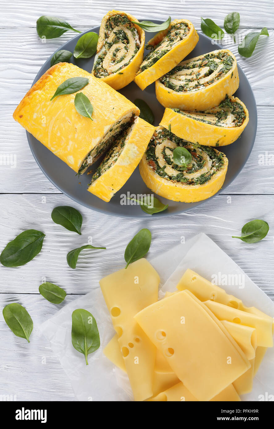 Delicious egg rolls avec un remplissage de mélange d'épinards, la feta et les carottes coupées en tranches sur la plaque grise sur table en bois avec des ingrédients à l'arrière-plan Banque D'Images