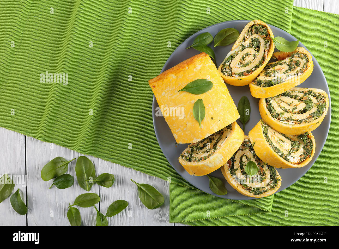 Roulade oeufs délicieux avec un remplissage de mélange d'épinards, la feta et les carottes coupées en tranches sur la plaque grise sur le tapis vert sur la table de bois, vue d'un Banque D'Images