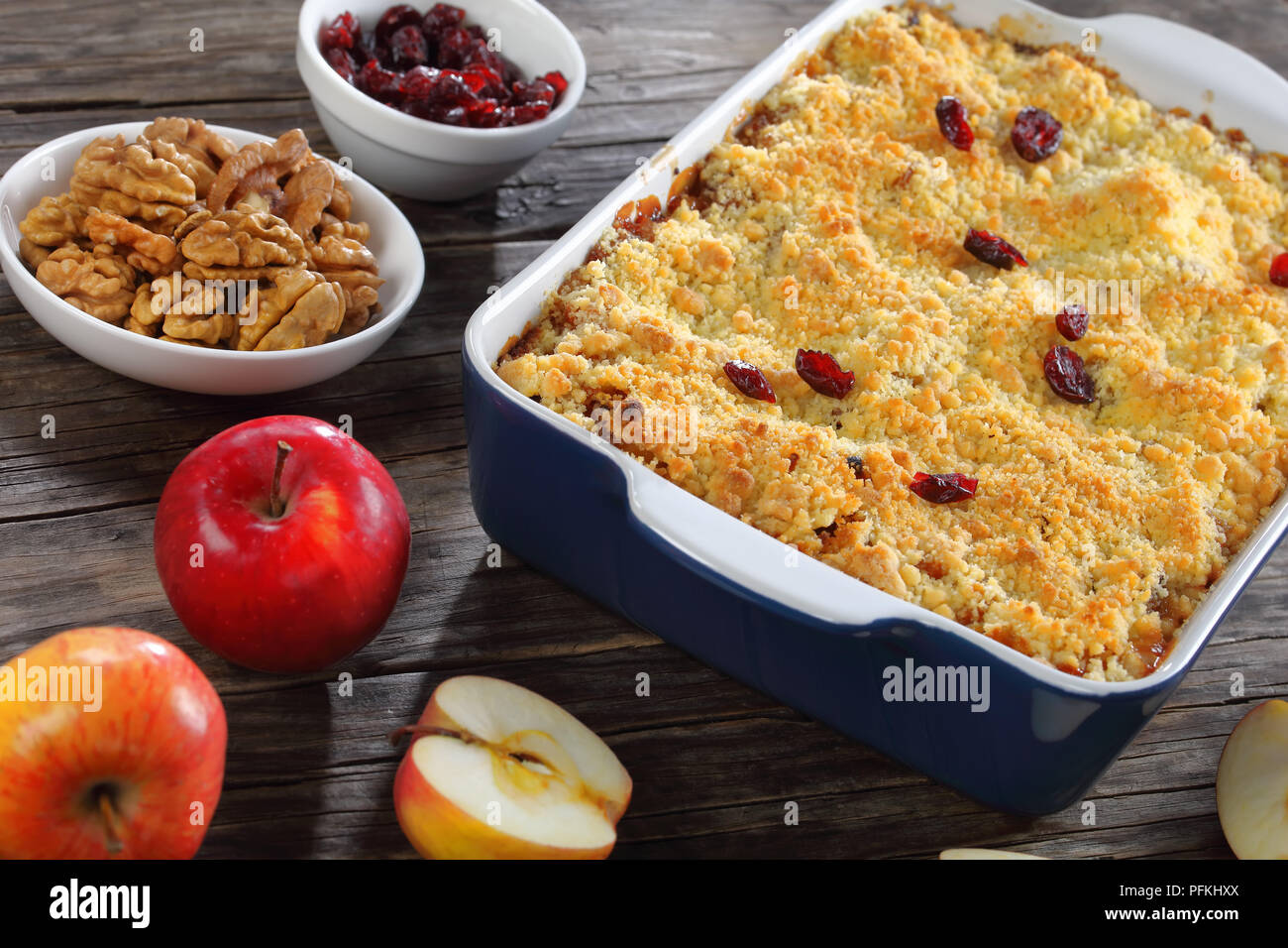Close-up of delicious crumble aux pommes ou apple crisp dans le plat de cuisson avec des ingrédients sur la table en bois sombre, sain et facile recette de petit-déjeuner de l'hiver, hor Banque D'Images