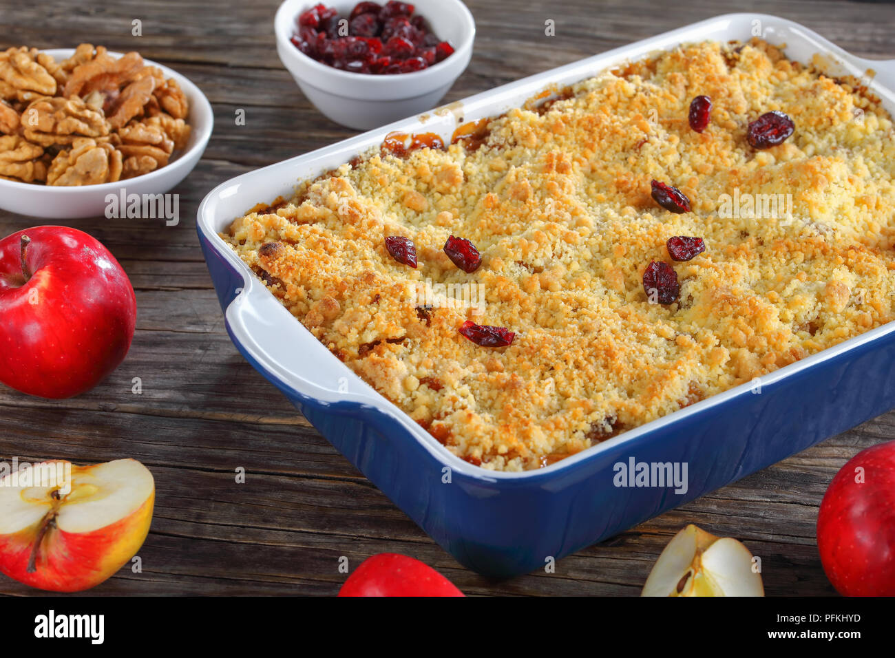 Close-up de crumble aux pommes fait maison ou apple crisp dans le plat de cuisson avec des ingrédients sur la table en bois sombre, sain et facile recette de petit-déjeuner de l'hiver, hori Banque D'Images