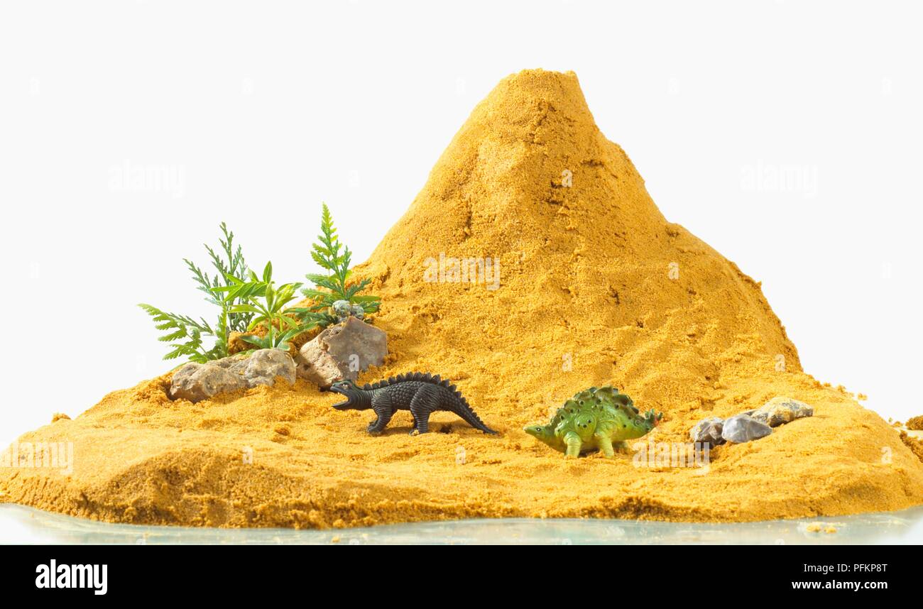 Volcan de type fabriqué à partir de sable avec des dinosaures et des plantes en plastique Banque D'Images
