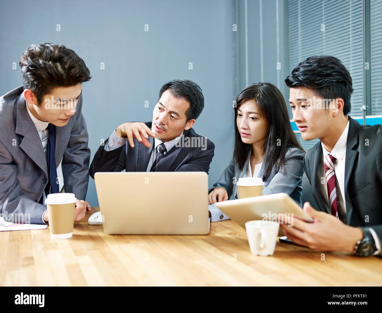 Les gens de l'entreprise asiatique meeting in office discuter affaires à l'aide d'un ordinateur portable. Banque D'Images