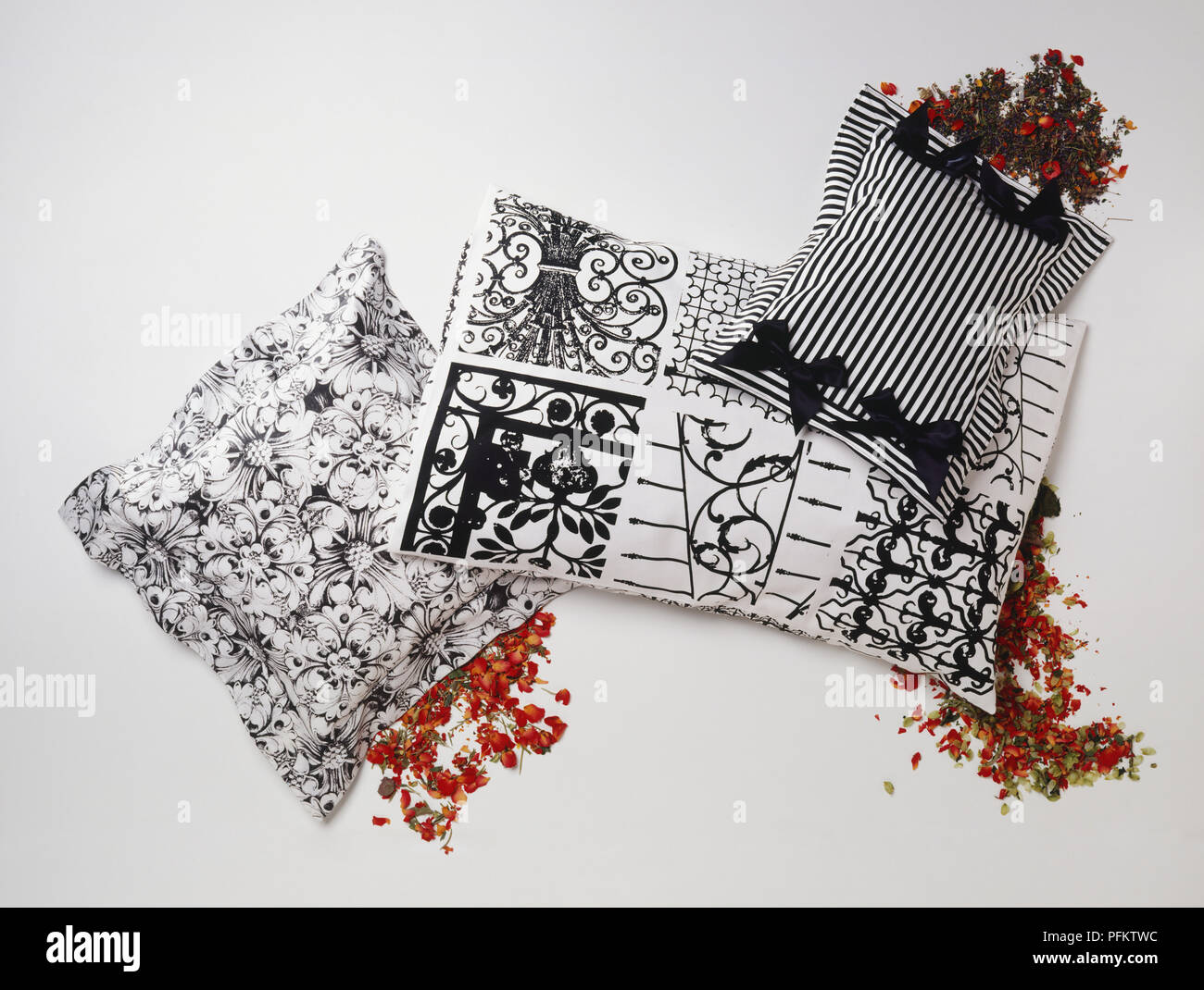 Trois coussins à motifs noir et blanc entouré de fleurs séchées rouge. Banque D'Images