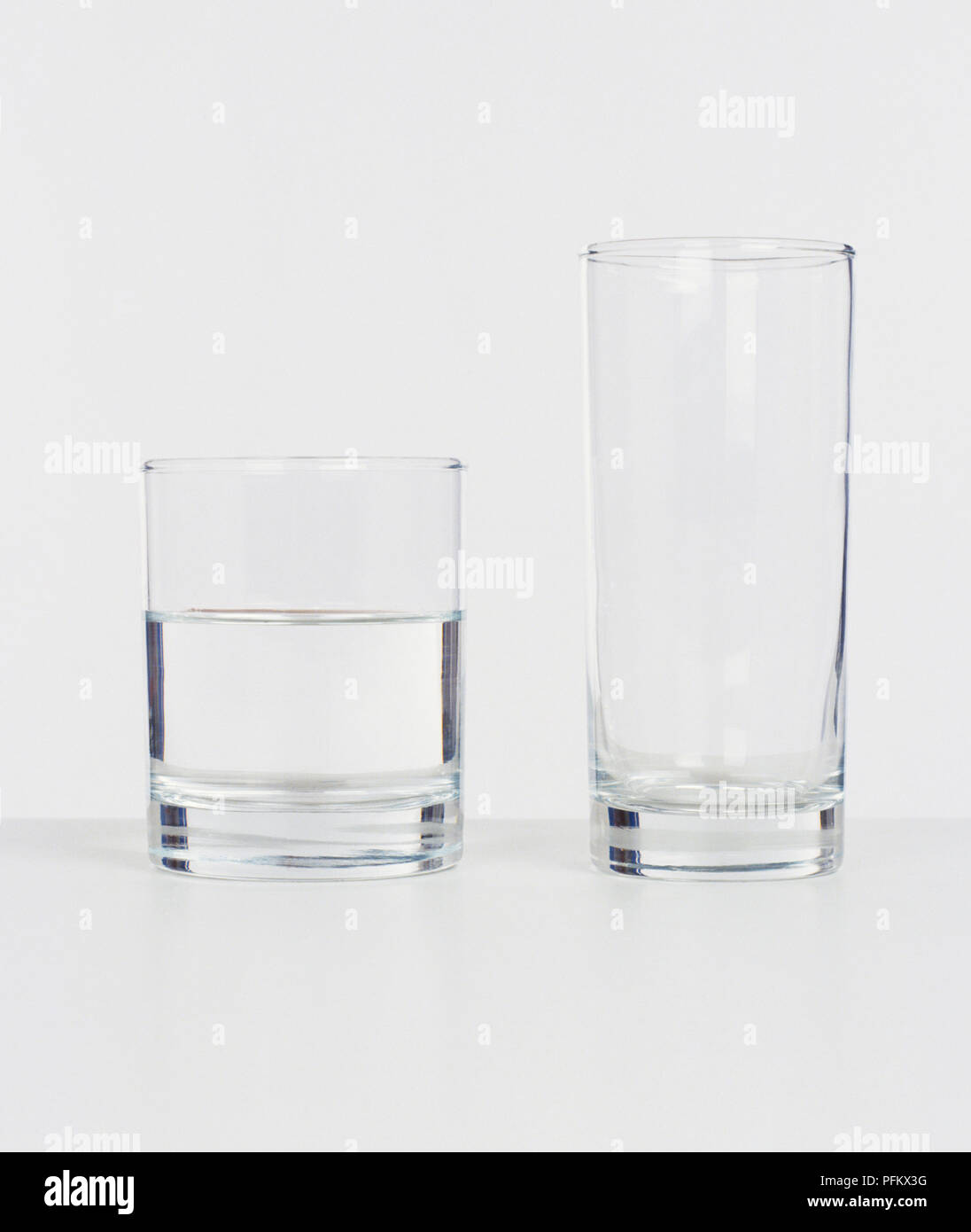 Grand verre à boire et plus petit verre à moitié plein avec de l'eau Banque D'Images