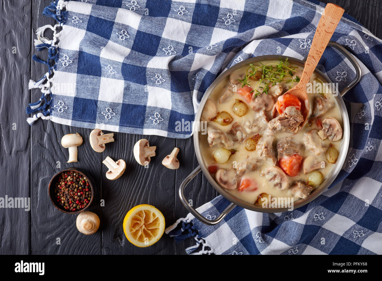 Blanquette de veau - Morceaux de veau, des champignons, des oignons perles, des herbes, des légumes avec sauce crémeuse dans une casserole avec une serviette de cuisine, poivre et bu Banque D'Images