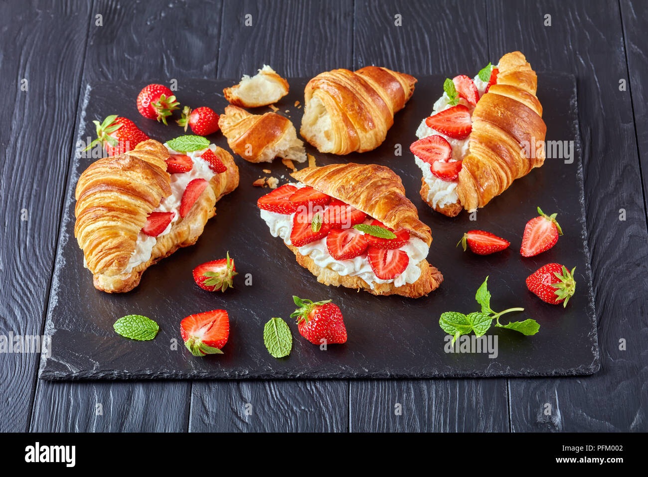 Petit-déjeuner d'été - un croissant frais mûrs sandwiches avec fraises et crème  fouettée fromage sur un bac en pierre sur une table en bois noir, close-up  Photo Stock - Alamy