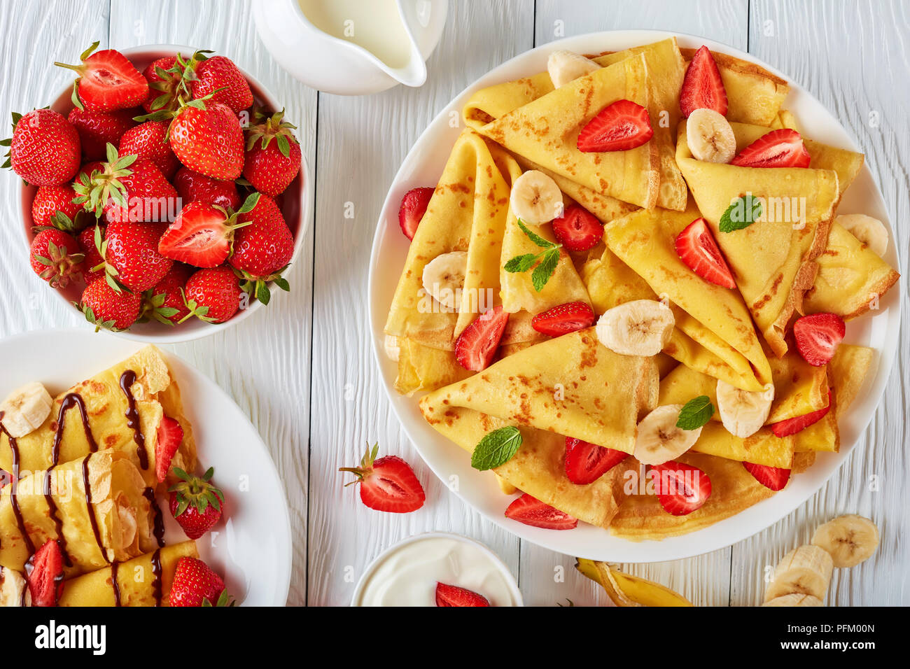 Crêpes minces ou des crêpes sur une plaque avec des fraises, des tranches de banane et de crème au chocolat, vue horizontale d'en haut Banque D'Images