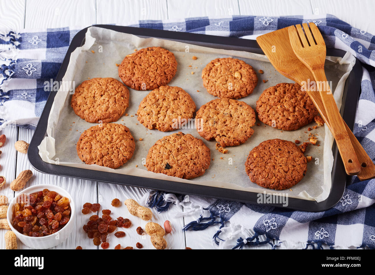 Biscuits fraîchement cuits au four avec des raisins secs et les arachides sur une plaque de cuisson avec des spatules en bois et cuisine serviette, vue horizontale à partir de ci-dessus, close-up Banque D'Images