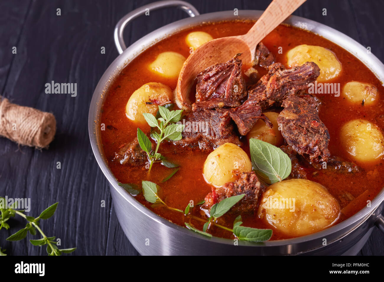 Un délicieux ragoût de boeuf pot avec de tendres cubes de viande, tout nouveau les pommes de terre, les carottes et les herbes dans un chaudron sur une table en bois noir avec bouquet de l'aaa Banque D'Images
