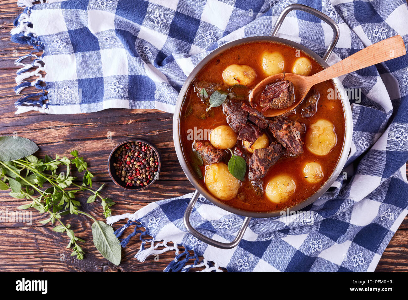 Ragoût de boeuf avec des cubes de viande tendre, ensemble de nouvelles pommes de terre, les carottes et les herbes dans une casserole de métal sur la vieille table en bois rustique avec des essuie-tout, des Irlandais c Banque D'Images