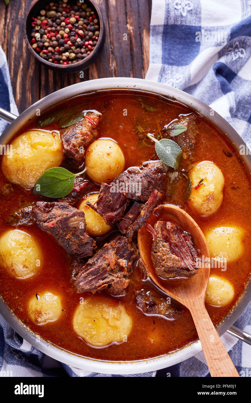 Ragoût de boeuf avec des cubes de viande tendre, ensemble de nouvelles pommes de terre, les carottes et les herbes dans une casserole de métal sur la vieille table en bois rustique avec des essuie-tout, des Irlandais c Banque D'Images