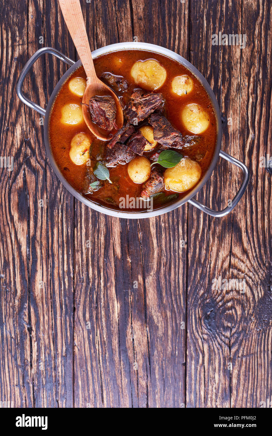 Ragoût de boeuf chaud avec de tendres cubes de viande, tout nouveau les pommes de terre, les carottes et les herbes dans une casserole de métal sur la vieille table en bois rustique, une cuisine irlandaise vertica, Banque D'Images