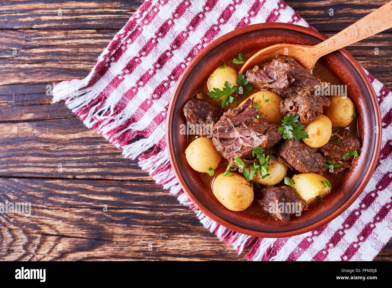 Ragoût de boeuf chaud avec de tendres cubes de viande, pommes de terre nouvelles, ensemble l'oignon et les herbes dans un bol d'argile sur la vieille table en bois rustique avec une cuisine irlandaise, serviette, hor Banque D'Images